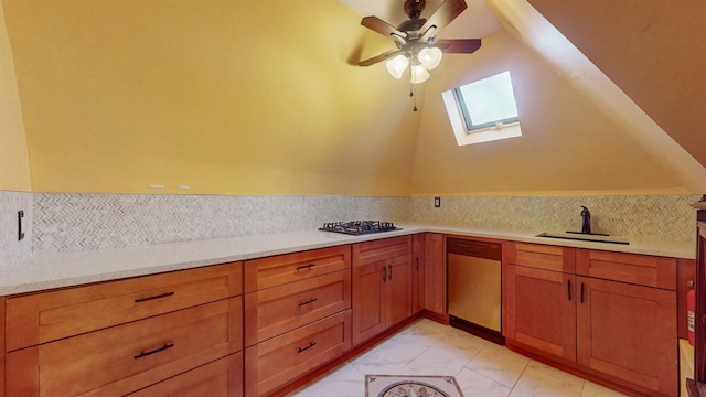 kitchen featuring a skylight, ceiling fan, sink, tasteful backsplash, and appliances with stainless steel finishes