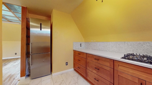 kitchen with stainless steel refrigerator, decorative backsplash, light hardwood / wood-style flooring, and gas stovetop