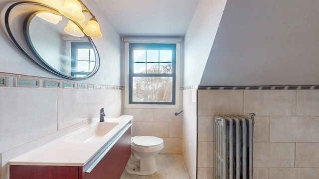 bathroom featuring tile patterned floors, vanity, tile walls, radiator heating unit, and toilet