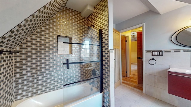 bathroom featuring tile patterned floors, vanity, combined bath / shower with glass door, and tile walls