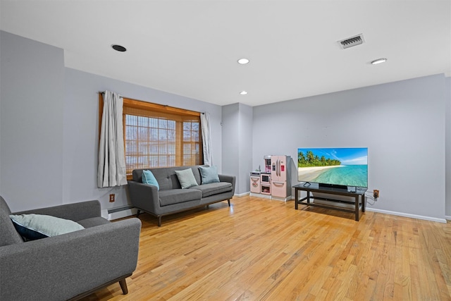 living room featuring light hardwood / wood-style floors and a baseboard heating unit