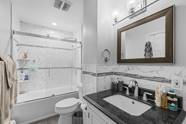 full bathroom featuring vanity, toilet, enclosed tub / shower combo, and tile walls