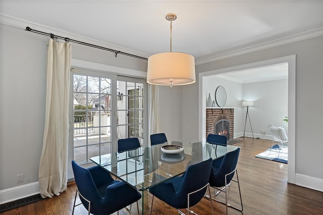 dining area featuring crown molding, a brick fireplace, and hardwood / wood-style floors