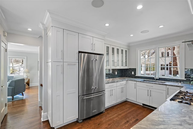 kitchen with stainless steel appliances, white cabinetry, sink, and light stone counters