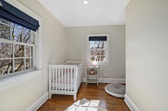 bedroom featuring dark hardwood / wood-style floors and a nursery area