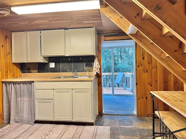 kitchen featuring wood walls, backsplash, white cabinets, sink, and wood ceiling