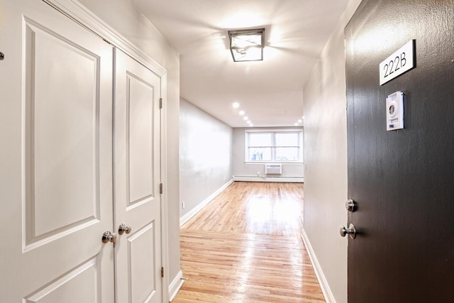 hallway with light wood-type flooring and baseboard heating