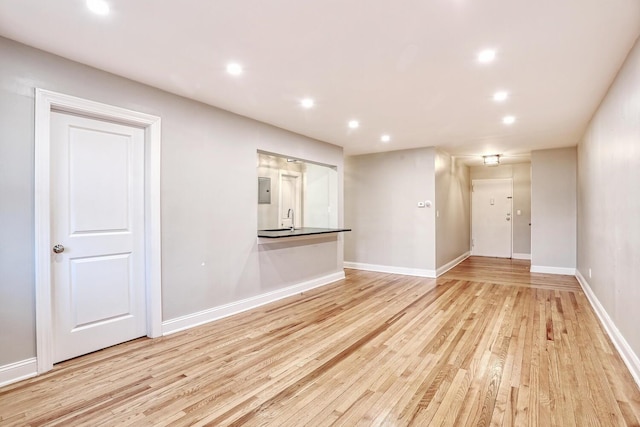 unfurnished living room featuring electric panel, light hardwood / wood-style flooring, and sink