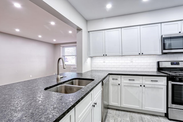 kitchen featuring white cabinets, sink, dark stone countertops, appliances with stainless steel finishes, and tasteful backsplash