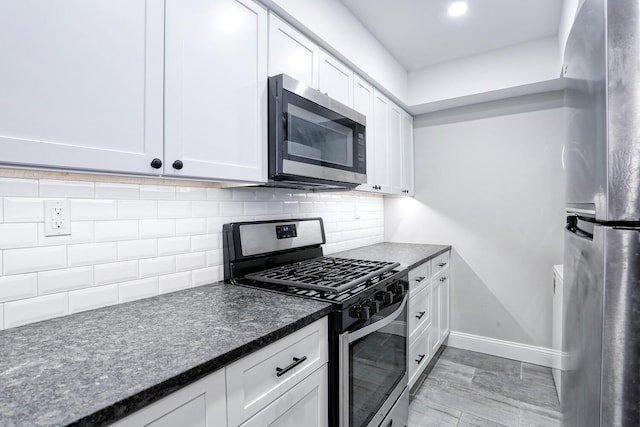 kitchen featuring white cabinets, appliances with stainless steel finishes, decorative backsplash, and dark stone counters