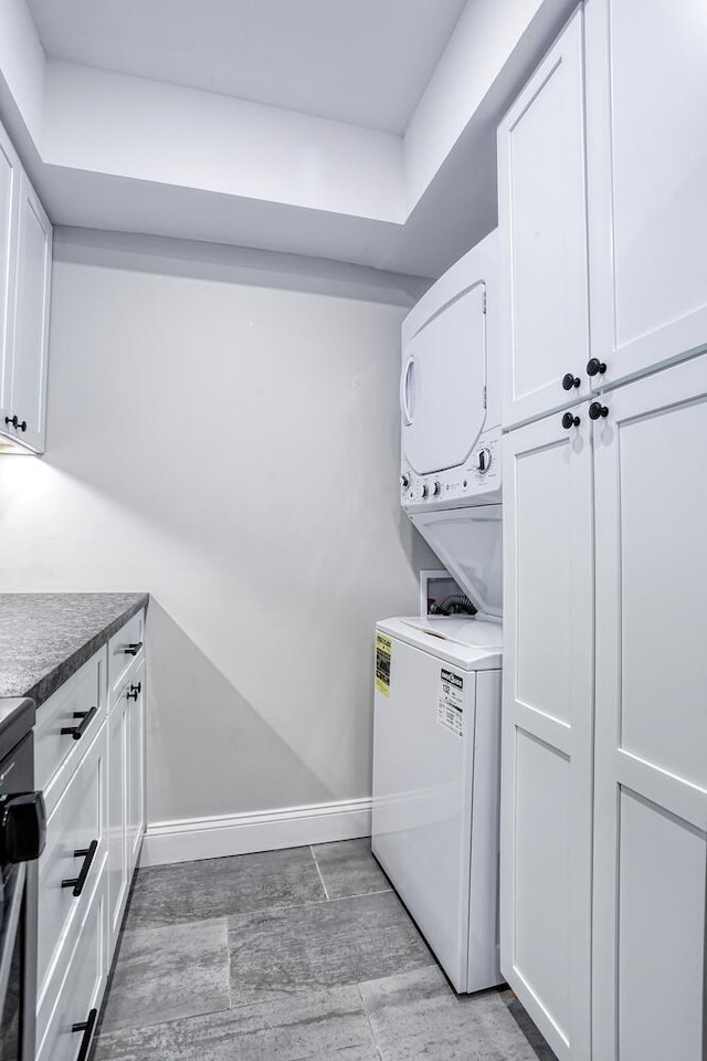 laundry area featuring cabinets and stacked washer and clothes dryer