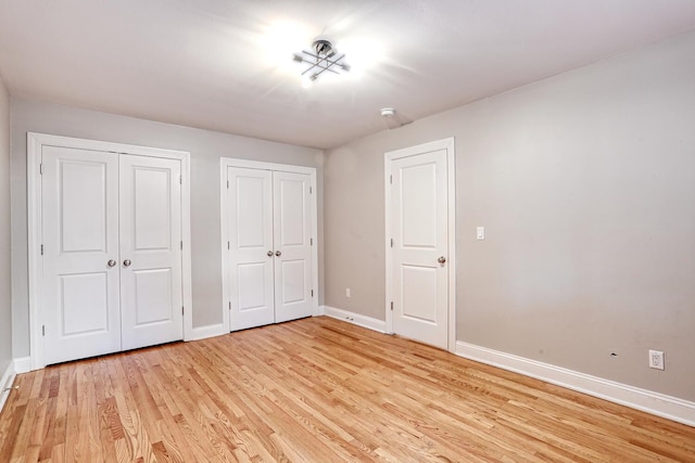 unfurnished bedroom with multiple closets and light hardwood / wood-style flooring