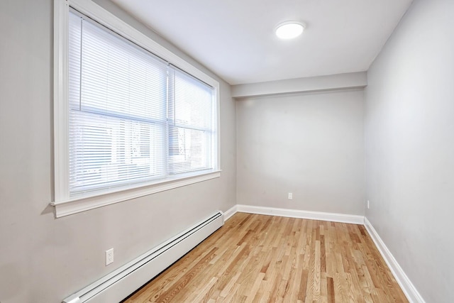 empty room with light wood-type flooring and a baseboard heating unit