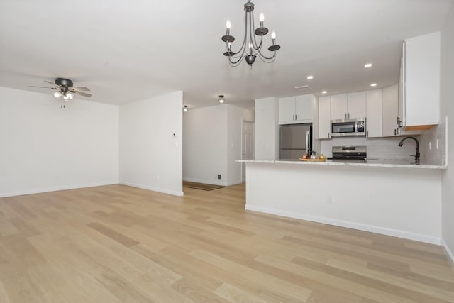 kitchen with white cabinetry, light stone countertops, light hardwood / wood-style flooring, kitchen peninsula, and appliances with stainless steel finishes