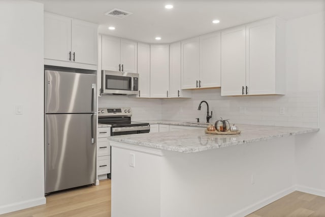 kitchen featuring light stone countertops, sink, appliances with stainless steel finishes, white cabinets, and light wood-type flooring