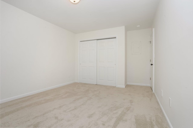 unfurnished bedroom featuring light carpet and a closet