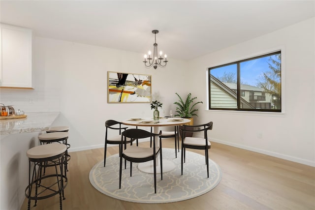 dining space featuring a notable chandelier and light wood-type flooring