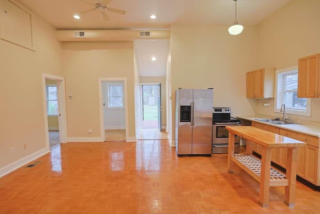 kitchen with sink, a towering ceiling, pendant lighting, and appliances with stainless steel finishes