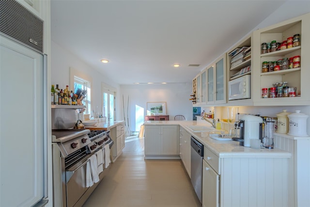 kitchen featuring white cabinets, sink, built in appliances, light hardwood / wood-style floors, and kitchen peninsula