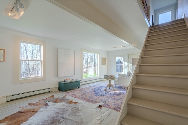 interior space with hardwood / wood-style floors, plenty of natural light, and a baseboard heating unit