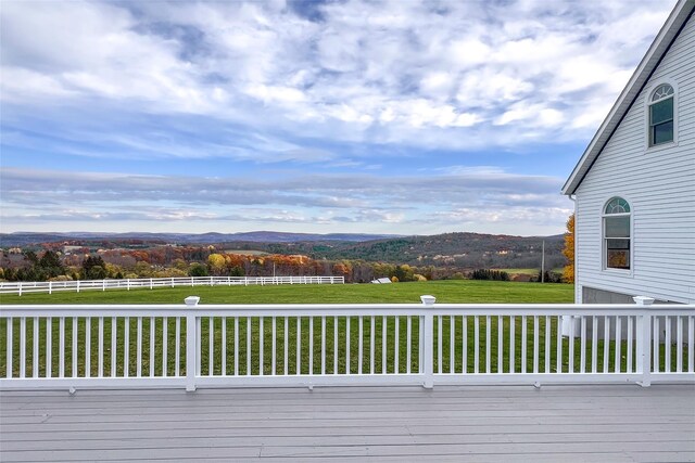 wooden deck featuring a mountain view, a rural view, and a yard