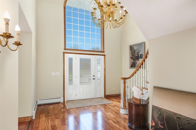 foyer entrance featuring a towering ceiling, a chandelier, and hardwood / wood-style flooring