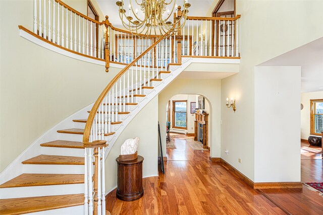 staircase with wood-type flooring, a high ceiling, and a chandelier