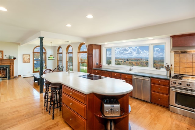 kitchen with a kitchen bar, appliances with stainless steel finishes, light hardwood / wood-style flooring, a center island, and hanging light fixtures