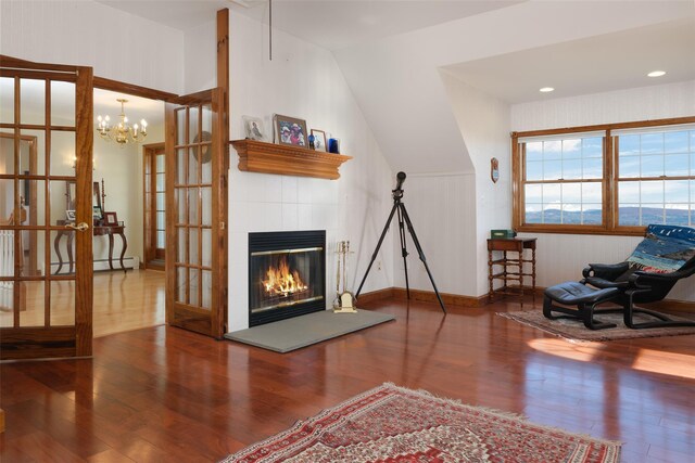 sitting room with hardwood / wood-style flooring, vaulted ceiling, an inviting chandelier, and french doors