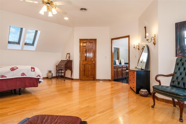 bedroom featuring hardwood / wood-style flooring, ceiling fan, a skylight, and ensuite bath