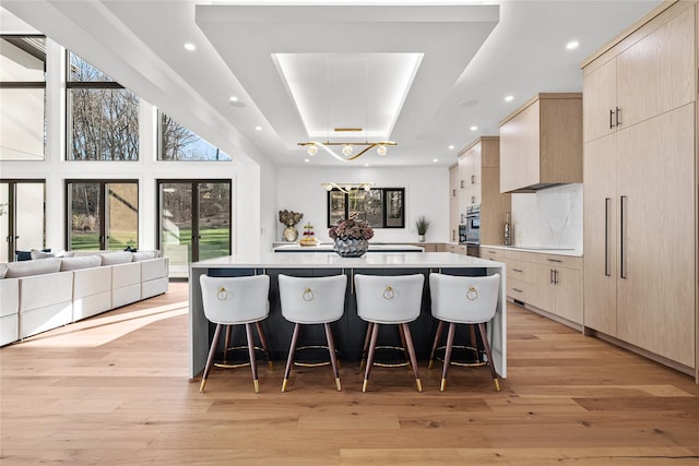 kitchen featuring a raised ceiling, plenty of natural light, and light wood-type flooring