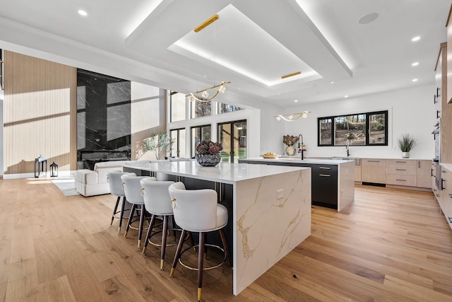 kitchen with pendant lighting, a large island, an inviting chandelier, and light hardwood / wood-style flooring