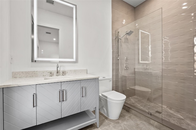 bathroom with tile patterned flooring, vanity, toilet, and a tile shower