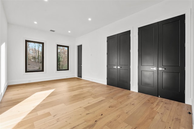 unfurnished bedroom featuring two closets and light hardwood / wood-style floors