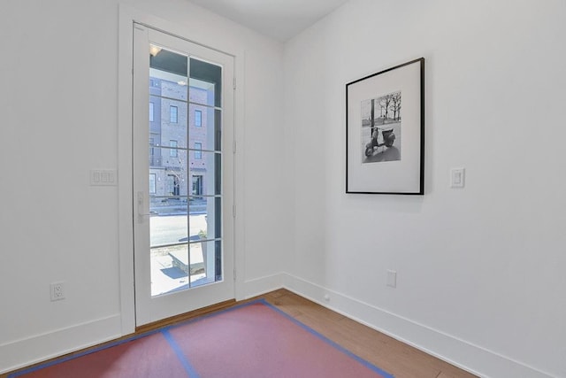 doorway featuring baseboards and wood finished floors