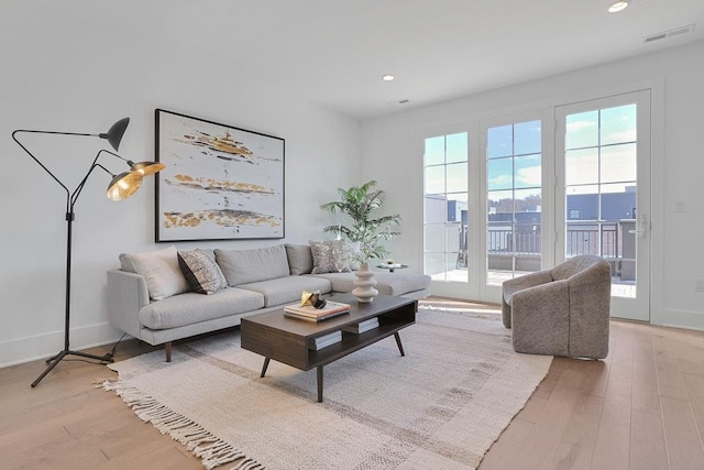 living room featuring baseboards, recessed lighting, visible vents, and light wood-style floors