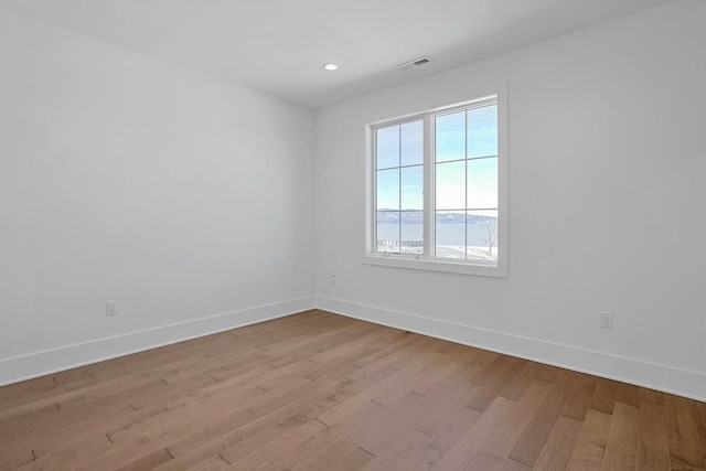 unfurnished room with light wood-type flooring, baseboards, visible vents, and recessed lighting