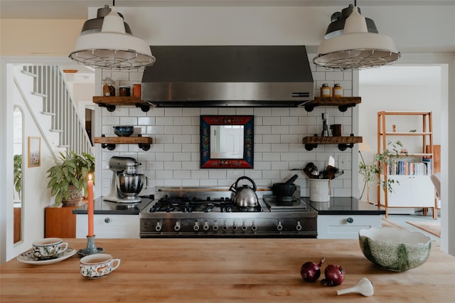 kitchen featuring pendant lighting, backsplash, wooden counters, black stove, and wall chimney range hood