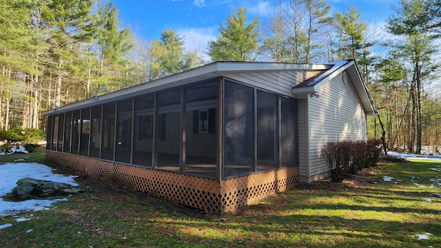 view of side of home with a lawn and a sunroom