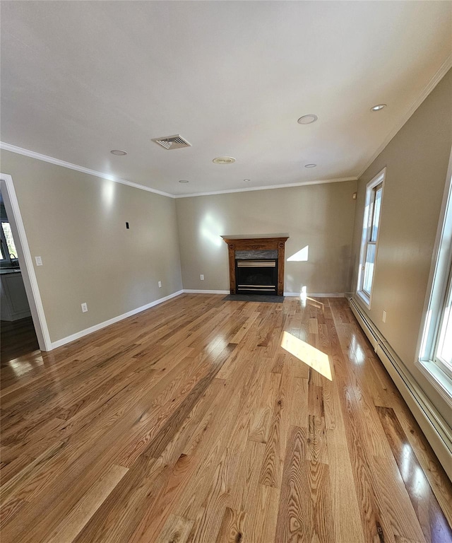 unfurnished living room with light hardwood / wood-style flooring, a baseboard heating unit, and crown molding