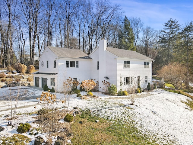 exterior space with driveway, a chimney, and an attached garage