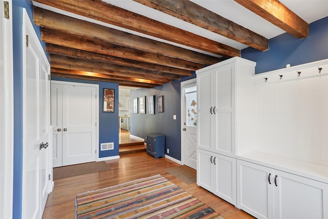 interior space featuring beam ceiling, visible vents, light wood-style flooring, and baseboards