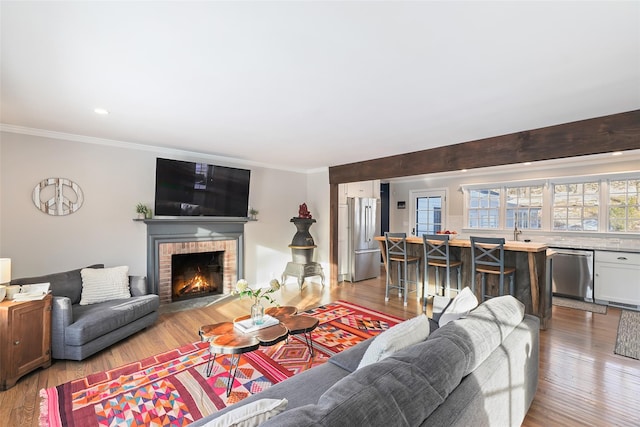 living area with recessed lighting, a fireplace, wood finished floors, and crown molding