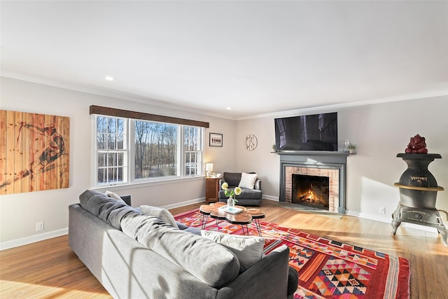 living room with crown molding, recessed lighting, wood finished floors, a lit fireplace, and baseboards