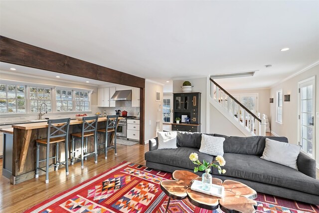 living area featuring crown molding, stairway, recessed lighting, and light wood-style floors