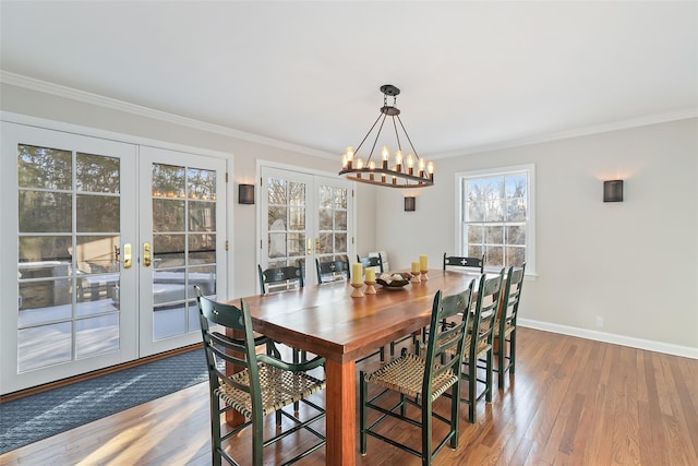 dining area featuring baseboards, wood finished floors, an inviting chandelier, crown molding, and french doors