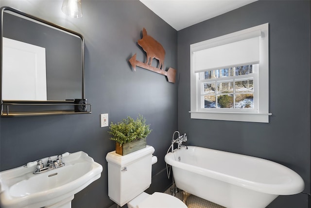 full bathroom featuring a freestanding tub, a sink, and toilet