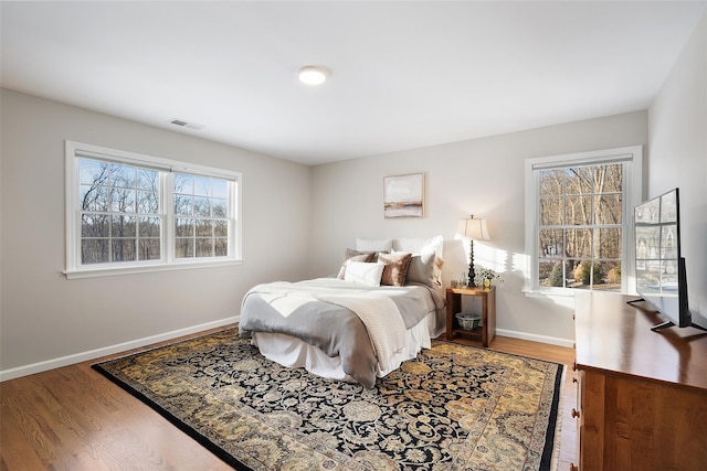 bedroom featuring visible vents, baseboards, and wood finished floors