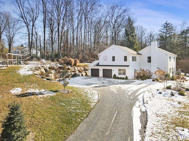 view of front of property featuring driveway, a chimney, and an attached garage