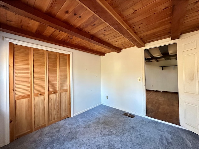 unfurnished bedroom with beamed ceiling, dark colored carpet, a closet, and wooden ceiling